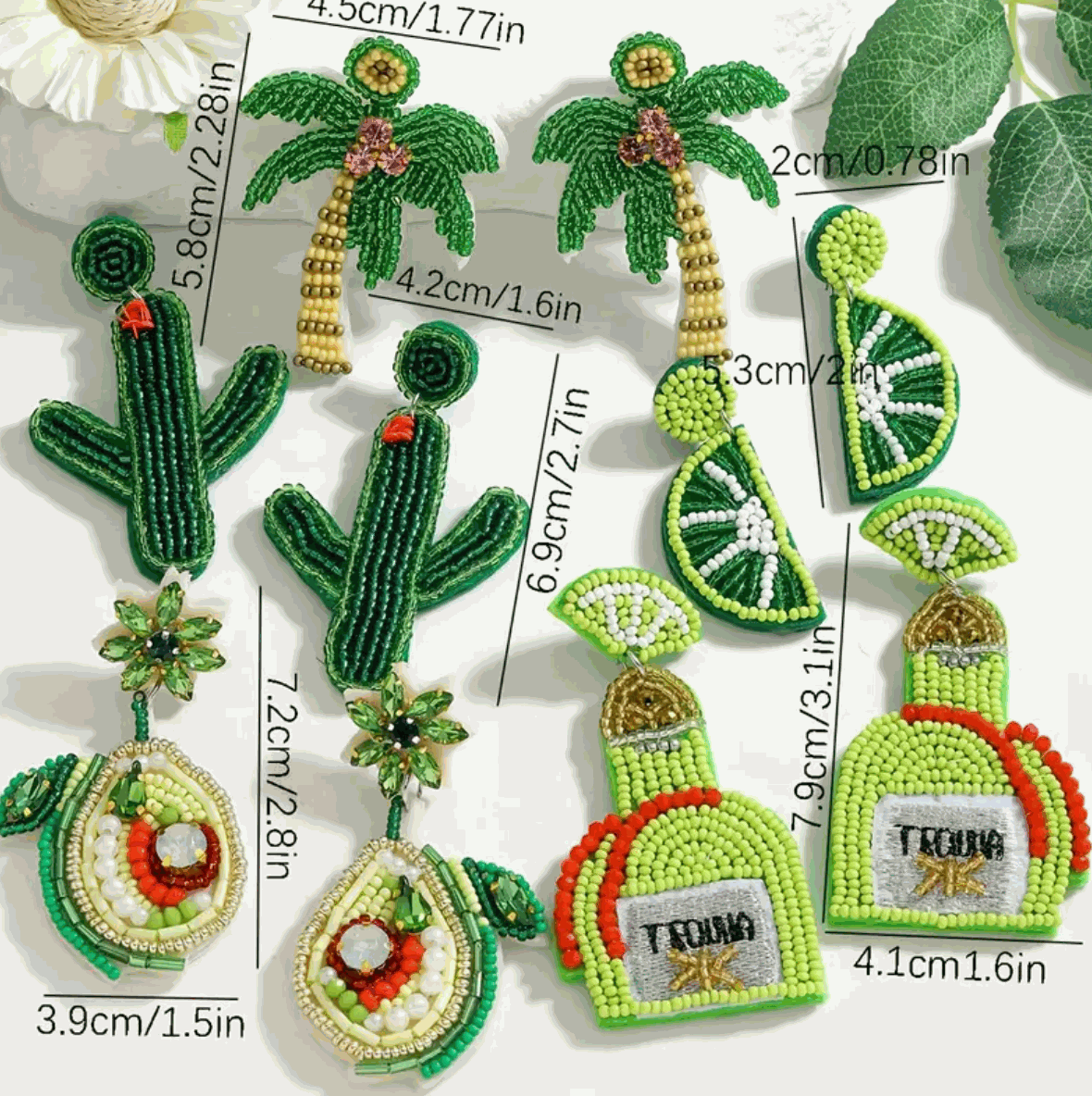 Colorful hand-beaded earrings featuring palm trees, cacti, lime slices, tequila bottles, and avocados.